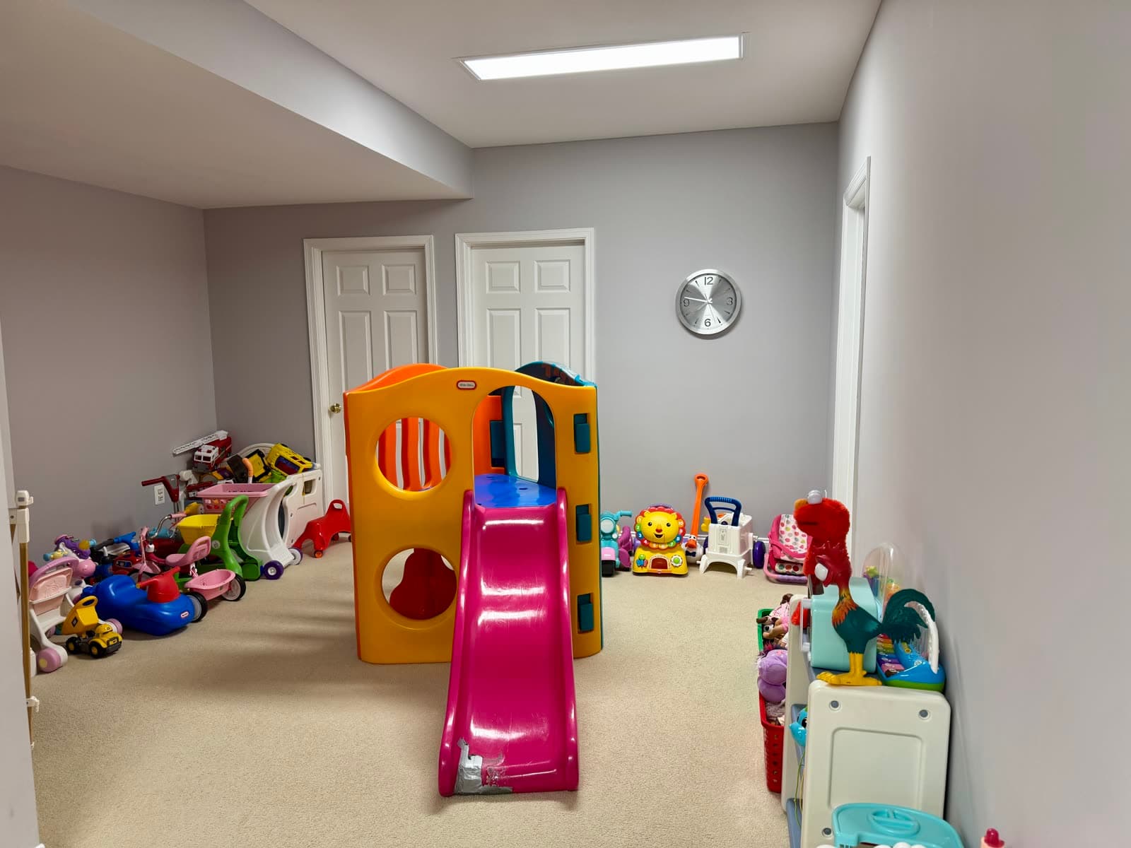 Play area with a small indoor slide and climbing toy, plus ride-on toys and activity tables along the wall.